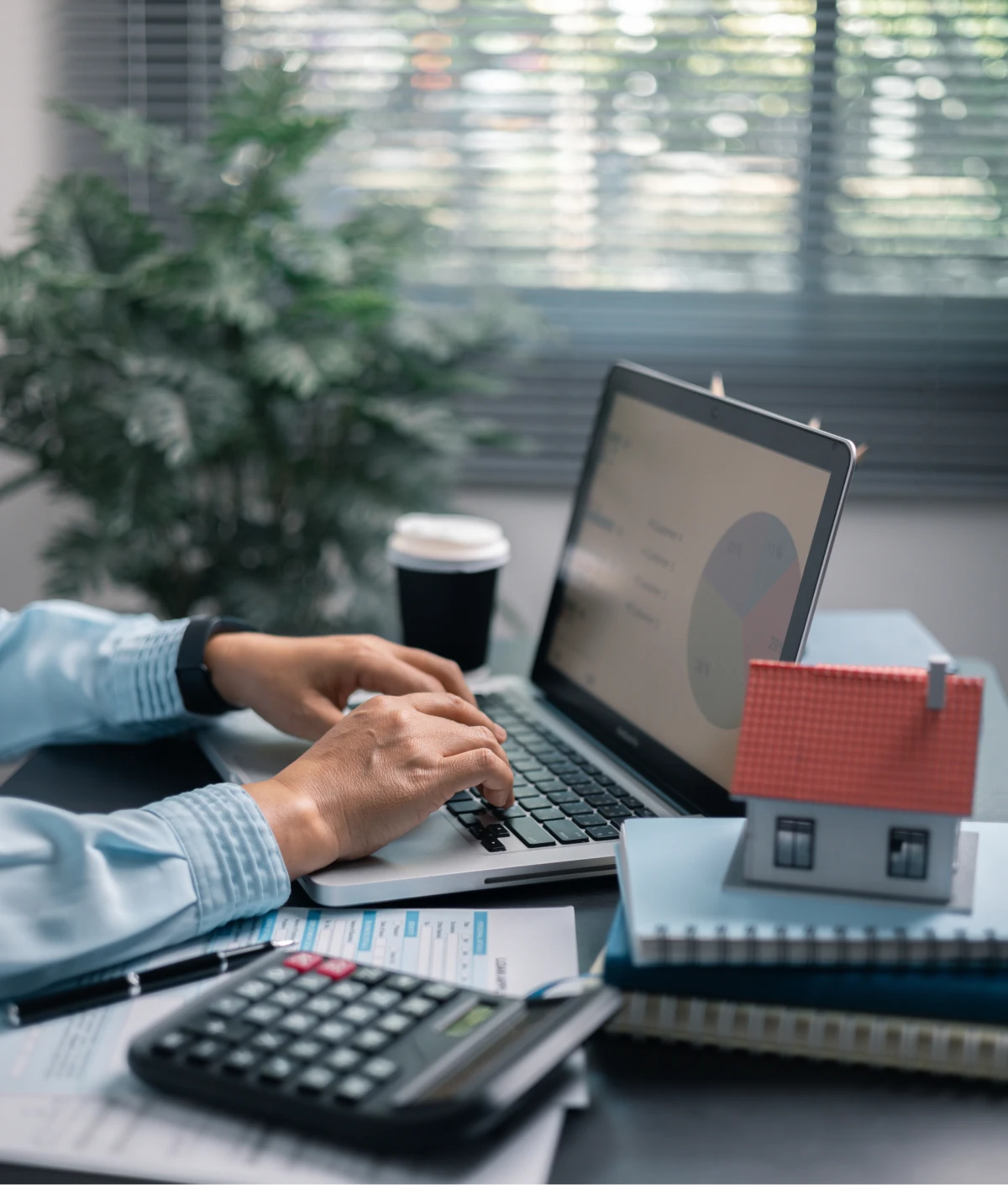 Person working on laptop with house model